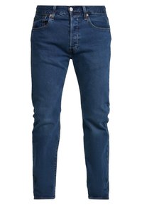 Tmavě modré džíny z denimu s úzkým střihem, pěti kapsami, zapínáním na knoflík a měděnými nýty. Hladká textura s minimálním vyblednutím.