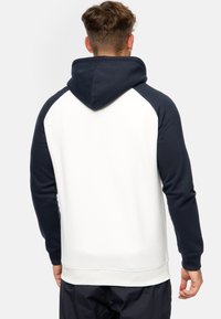 Sudadera con capucha de color blanco en el cuerpo y mangas raglán azul marino. Presenta una textura suave y puños y dobladillo acanalados para un acabado ajustado.