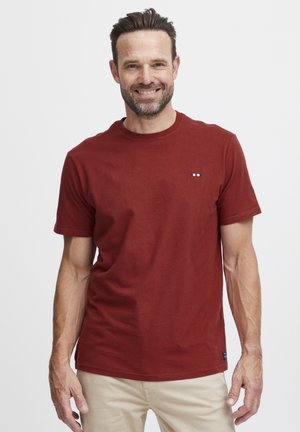 Camiseta de algodón roja con cuello redondo, mangas cortas y un pequeño logo en el pecho. Diseñada con un ajuste clásico y relajado.