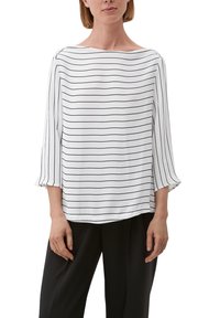 Blusa bianca con righe orizzontali nere, scollo a barca, maniche a tre quarti con polsini elasticizzati, tessuto leggero e vestibilità comoda.