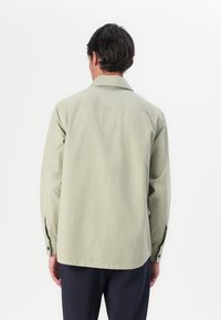 Lange mouwen shirt in lichtgroene katoen, met een klassieke kraag, rechte snit en knoopmanchetten. Gladde textuur en minimale details.