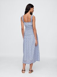Maxikjole i blå blomstermønster, med volangstroppar, en tettsittende bodice og en lagdelt skjørt. Laget av lett, flytende materiale.
