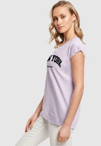 Lyse lilla kortærmet t-shirt med en iøjnefaldende sort "NEW YORK" grafik og en afslappet pasform, lavet af blødt bomuldsstof.