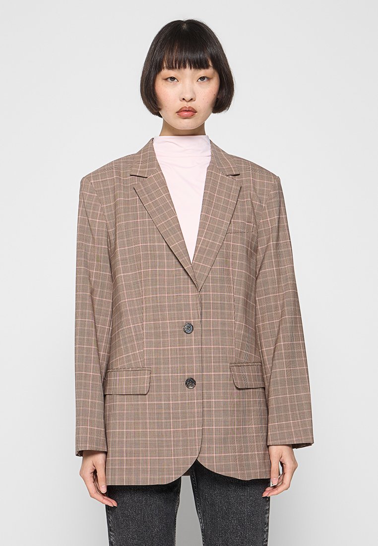 Bruin geruit blazer met een ontspannen pasvorm, twee voorzakken, enkele knoopsluiting en subtiele gestructureerde stof. Lange mouwen en revers.