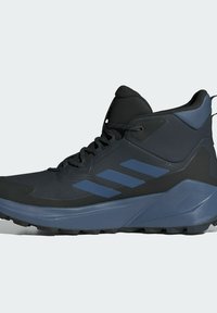 Zapatilla alta en negro y azul oscuro con una parte superior texturizada, logo de tres franjas, puntera reforzada y suela de goma resistente para mayor tracción.
