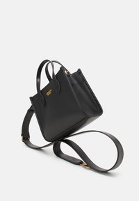 Czarna skórzana torebka z złotym logo, podwójnymi uchwytami na górze, odpinanym paskiem na ramię, usztywnionym kształtem i gładką fakturą.