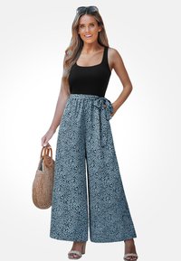 Pantalones de pierna ancha azules con un patr�ón moteado negro y un cinturón atado en la cintura. Combinados con una camiseta sin mangas negra y una bolsa de mimbre marrón.