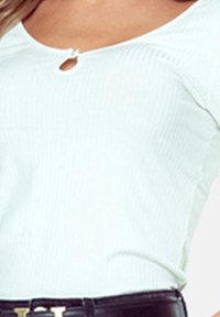 Biała prążkowana bluzka z okrągłym dekoltem i małym detalem w formie dziurki. Bluzka jest zestawiona z czarnym paskiem z złotą klamrą.