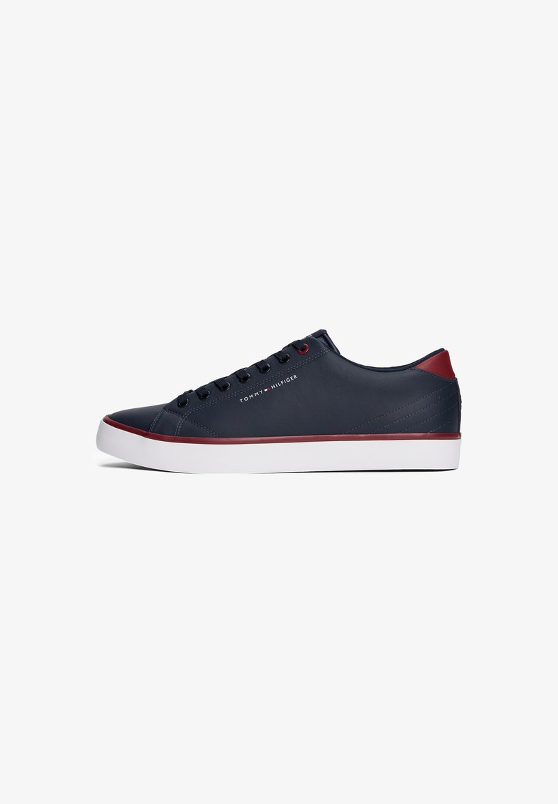 Baskets basses bleu marine avec semelle blanche, accents rouges au talon et sur les bordures, lacets noirs et logo « Tommy Hilfiger » sur le côté.