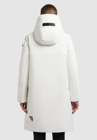 Hvid pufferjakke med en stor hætte, elegant design og sidelommer. Inkluderer et logo mærke nær kanten. Blød, glat stoftekstur.