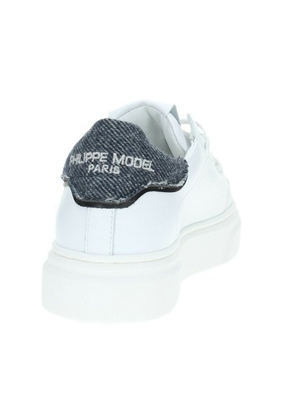 Sneaker bianco con una superficie in pelle liscia, dotato di un pannello posteriore in denim scuro con branding ricamato e una suola spessa bianca.