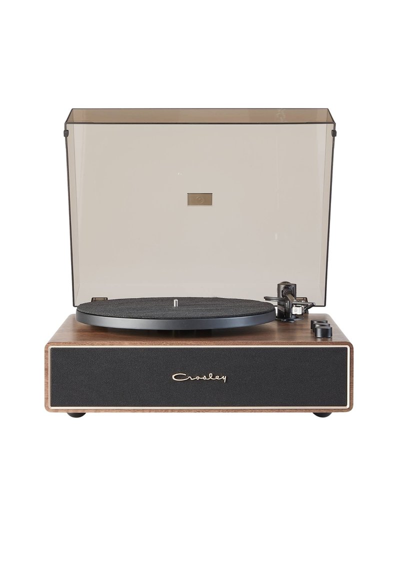 Giradiscos de vinilo con base de madera, plato negro, rejilla de altavoz de tela gris y tapa de polvo transparente. Controles a los lados.