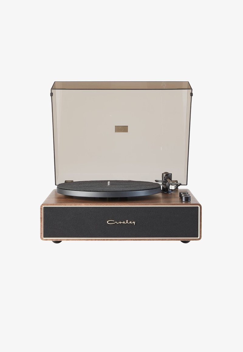 Giradiscos de vinilo con base de madera, plato negro, rejilla de altavoz de tela gris y tapa de polvo transparente. Controles a los lados.