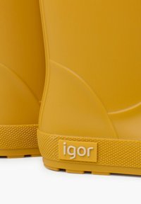 Stivali di gomma gialli con una superficie liscia e un design stampato. Presentano una suola testurizzata e un'etichetta con logo di colore giallo chiaro sul lato.