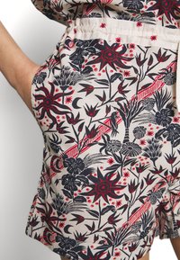 Bloemenpatroon stof shorts met een crèmekleurige achtergrond en blauwe en rode botanische ontwerpen, elastische tailleband en zijzakken.