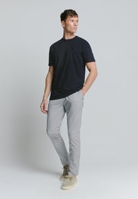 Marine gestreepte t-shirt met korte mouwen, gecombineerd met lichtgrijze slim-fit broek en beige schoenen. De outfit heeft een ontspannen pasvorm en een casual stijl.