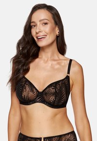 Czarny stanik z koronką w liściasty wzór, półprzezroczysty materiał oraz regulowane ramiączka. Ozdobiony falbaniastymi brzegami i zapięciem na klamrę.