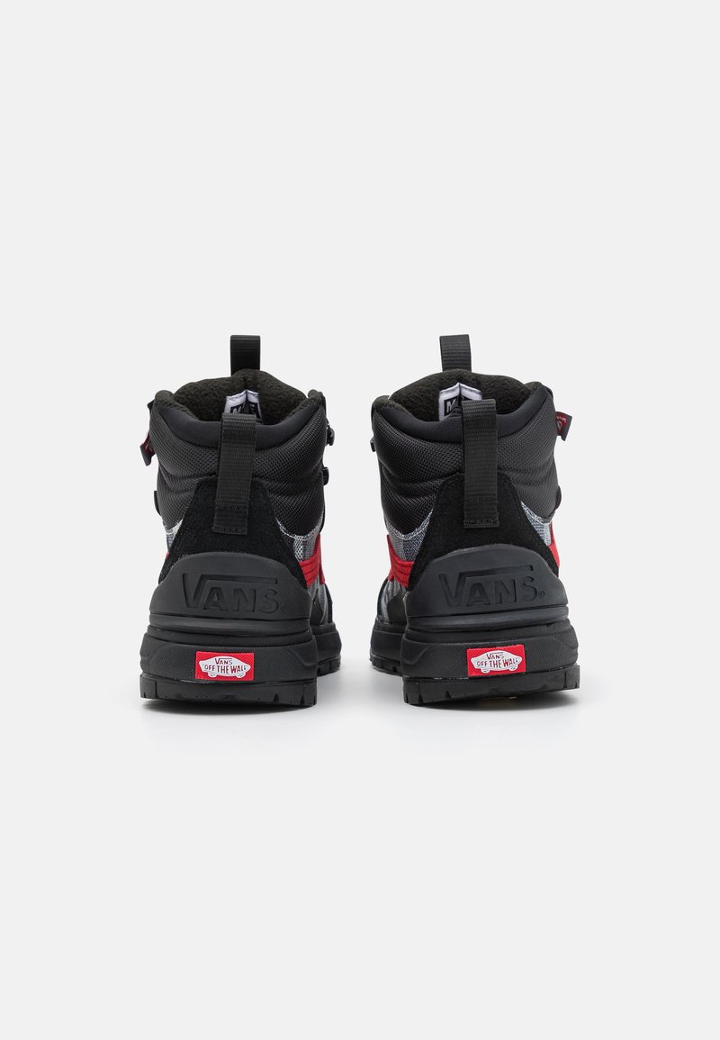 Zapatillas altas negras y rojas con un tejido texturizado y suela de goma, que cuentan con tiradores y la marca Vans en el talón y la lengüeta.
