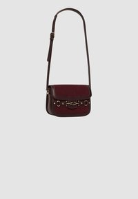 Borsa a tracolla in pelle bordeaux con dettagli in suede, chiusura a pattina, ferramenta decorativa in metallo e tracolla regolabile.