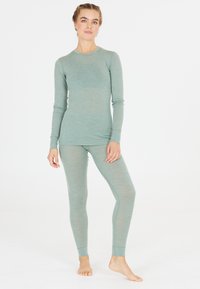 Lichtgroene langslavige top en bijpassende strakke legging van zachte, textuurstof met een subtiele glans. Eenvoudig, figuurvolgend ontwerp.