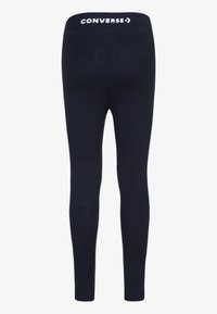 Marine leggings laget av elastisk stoff med høy livlinje som har en hvit "CONVERSE"-logo. Glatt tekstur og tettsittende design.