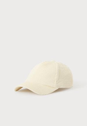 Beige kordfløjl baseballkasket med buet skyggelap placeret på en hvid flad overflade.