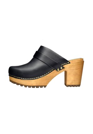 Zoccolo in pelle nera con un ampio cinturino, tacco in legno e suola testurizzata. Caratterizzato da cuciture dorate e accessori in metallo.