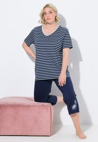 T-shirt a maniche corte a righe blu navy con scollo a V, abbinato a pantaloni capri blu navy uniti con ricami floreali sull'orlo.