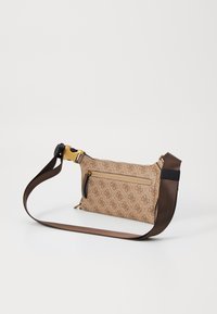 Ruskea crossbody-laukku, joka on valmistettu kuviolastasta, jossa on vetoketjullinen tasku, kultaiset yksityiskohdat ja irrotettava säädettävä hihna.