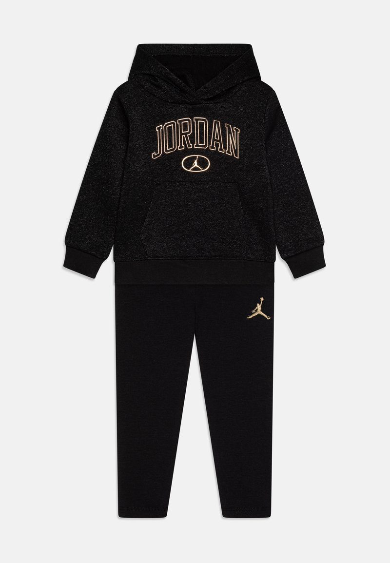 Černá mikina s kapucí s nápisem "JORDAN" a logem vyšitým zlatou nití a černé teplákové kalhoty s výrazným zlatým logem na levé noze. Vyrobeno z měkkého materiálu.