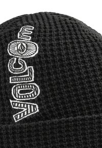 Sort strikket hue med et struktureret mønster; har et hvidt broderet logo med indviklede designelementer.
