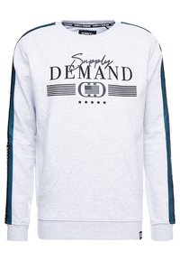 Sweatshirt gris clair avec le texte "Supply Demand", des rayures noires, un logo, des étoiles sur le devant et des rayures bleu foncé le long des manches.