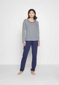 Lange mouwen gestreepte top in marineblauw en wit katoen met een ronde hals, gecombineerd met marineblauwe pants met trekkoord in een zachte, comfortabele stof.