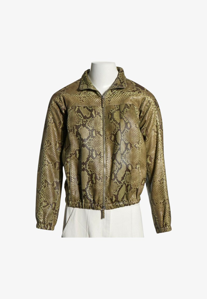 Veste marron clair zippée avec motif peau de serpent et poignets et ourlet élastiqués, exposée sur un buste de mannequin blanc.
