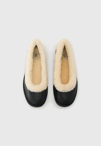 Ballerine in pelle nera con morbida fodera e rifiniture in pelliccia di pecora color crema. Design a punta arrotondata, suola robusta e logo visibile all'interno.