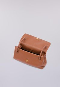 Sac à main en cuir tan avec une texture lisse, une fermeture à pression sécurisée et deux poignées rondes. L'intérieur est ouvert et spacieux.