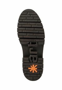 Suela de zapato de goma negra con superficie texturizada, que presenta un patrón de ladrillo y un logo naranja en el centro, mejorando el agarre y la tracción.