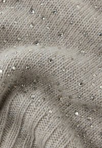 Szara dzianina o fakturalnym wzorze, ozdobiona drobnymi, błyszczącymi kryształkami rozsianymi po całej powierzchni.
