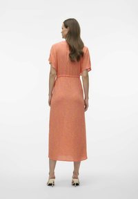 Vestido midi de estampado floral en tonos rosas, con mangas cortas, cintura ajustada y dobladillo fluido. Llevado con mulas de tacón de color claro.