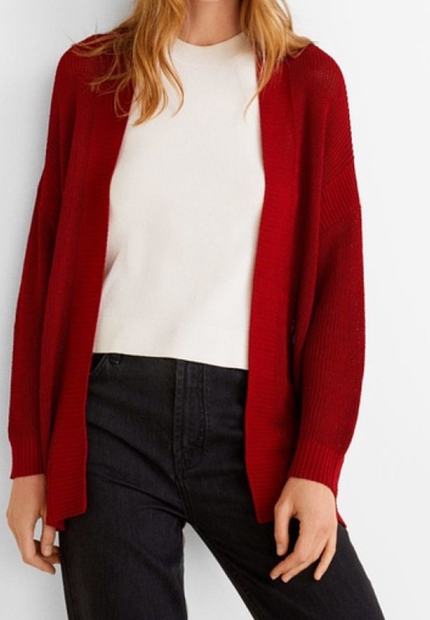 Long cardigan rouge avec texture côtelée, ouverture sur le devant et coupe décontractée, porté avec un haut blanc et un jean foncé. Design simple et moderne.