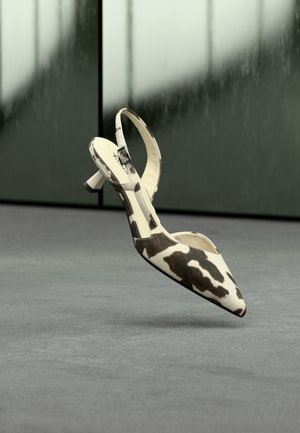 Escarpin à bout pointu avec bride arrière en cuir imprimé motif vache. Caractérisé par un talon élancé, une sangle ajustable avec boucle métallique et un intérieur lisse.