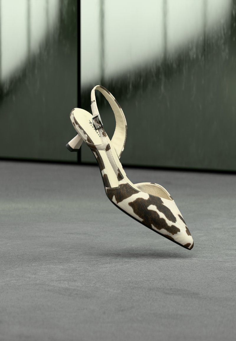 Escarpin à bout pointu avec bride arrière en cuir imprimé motif vache. Caractérisé par un talon élancé, une sangle ajustable avec boucle métallique et un intérieur lisse.