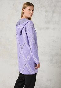 Lichtpaarse gebreide cardigan met een capuchon, met een ruitenpatroon en textuurstof. Het kledingstuk heeft lange mouwen en een relaxte pasvorm.