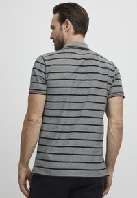 Gråstripet polo skjorte med svarte striper, en knappet krage og ribbede ermekanter med røde detaljer. Slim fit design.
