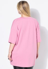 Rosa übergroßes T-Shirt mit kurzen Ärmeln, rundem Halsausschnitt und glatter Baumwolltextur. Das Design ist einfach, ohne Muster oder Akzente.
