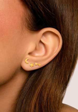 Goldene Steckerohrringe mit Designs von einer Halbmond, einem Stern und einem Pfeil. Glatte, glänzende Oberflächen mit einer minimalistischen Ästhetik.