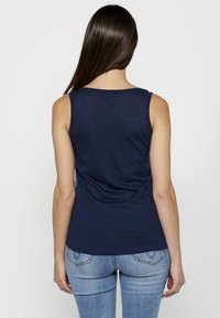 Top sans manches bleu marine avec une texture lisse, un encolure ronde et une coupe ajustée. Présente un motif subtil sur le côté.