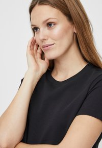 Fekete pamut póló kerek nyakkivágással és rövid ujjakkal, sima textúrával és testhezálló fazonnal. Nincsenek észlelhető mintázatok vagy díszítések.
