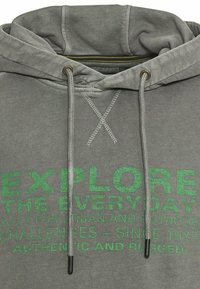 Gray hoodie with a drawstring hood. Features green text: "EXPLORE THE EVERYDAY" and "AUTHENTIC AND RUGGED." Cotton blend material.