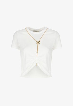 Maglietta corta in cotone bianco con dettaglio anteriore intrecciato. Presenta una catena dorata con un fiocco e una texture sottile. Maniche corte.